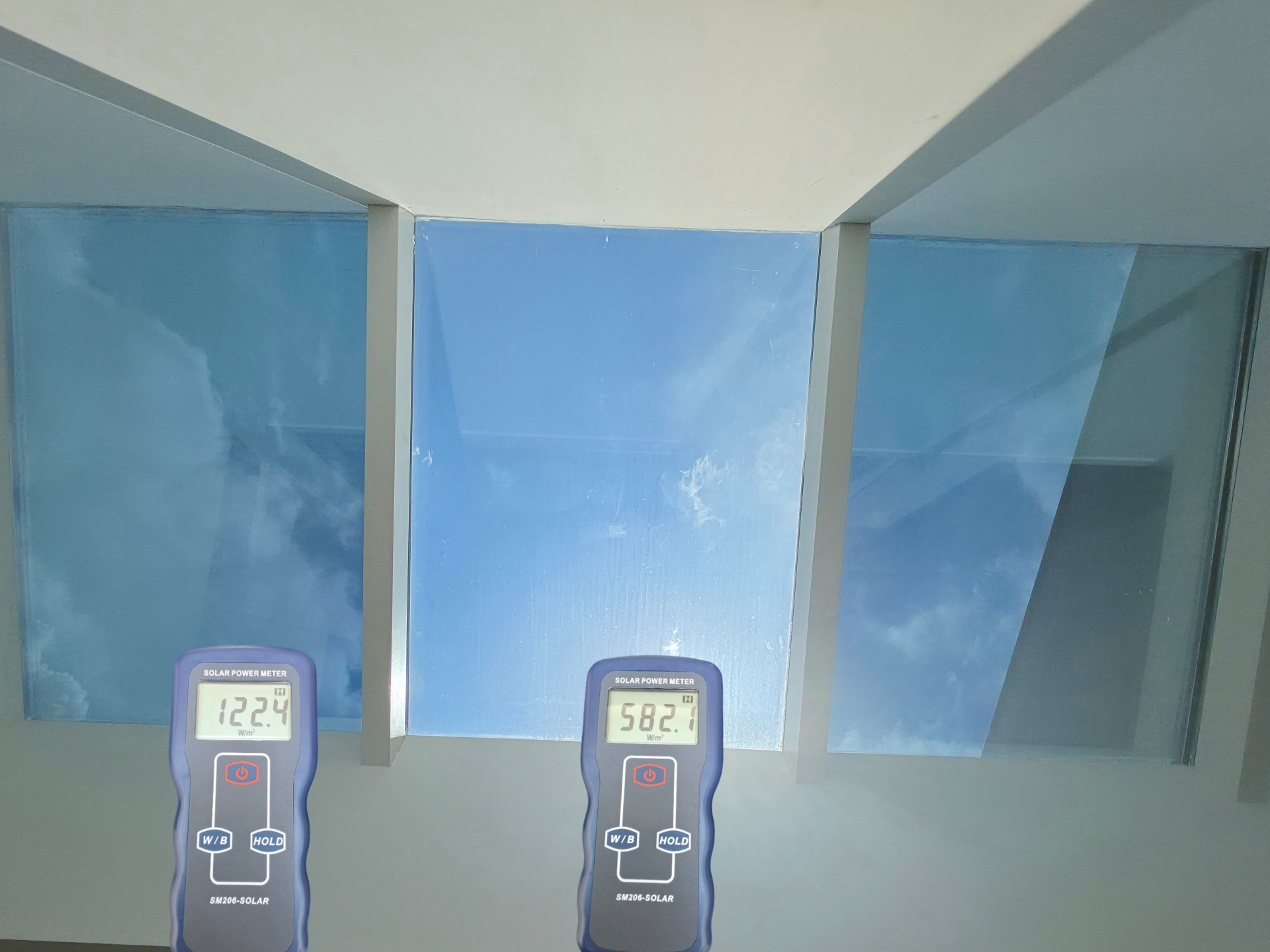 Solar power meter meting bij raam met zonwerende glasfolie en raam zonder folie